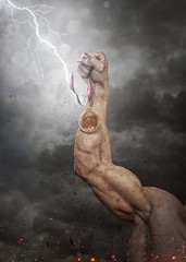 Obraz na płótnie Canvas Male hand holding gold medal against the dramatic sky