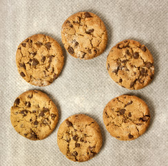 Freshly baked chocolate chips cookies, forming a circle frame for a text or logo