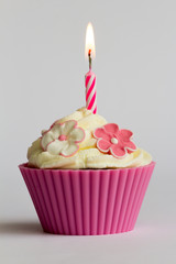 pink cupcake with burning candle close up