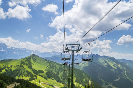 Beautiful green landscape with white clouds in the French Alps mountains and cable transportation