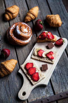 delicious breakfast with strawberries and sweet bun on wooden background. Fruit, food, chocolate