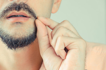 Fototapeta premium man with a beard and mustache shows and pulls the ends