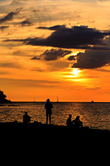 Fototapeta premium Silhouette of happy people on the beach at sunset