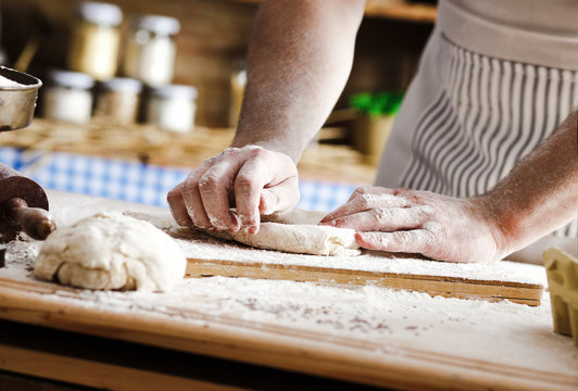 Close up of male baker hands kneading the dough with flour powder.
