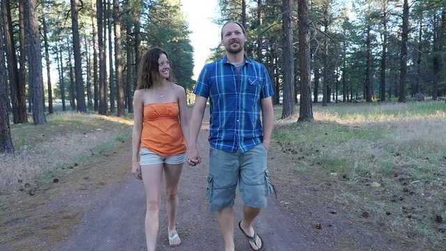 A Man And Woman Holding Hands, Walking In The Forest