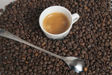 Long spoon to coffee latte and fresh espresso cap. Background dark coffee beans