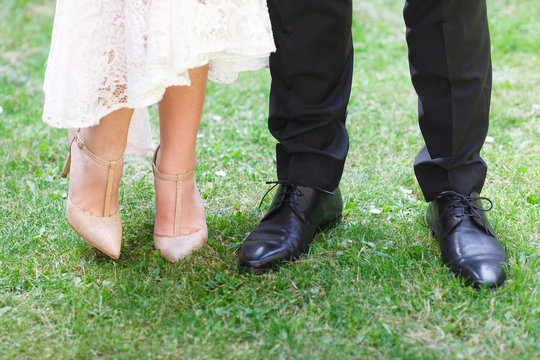 Close-up of bride's and groom's feet standing on green grass