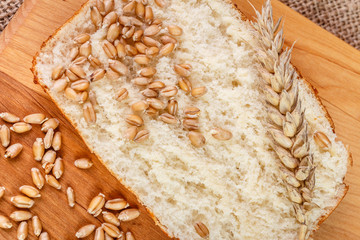 Fresh slices whole bread and wheat on the wooden board on burlap