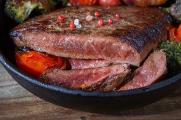 Beef steak medium rare with vegetables on a cast iron skillet. still life of food in low key. a dish of European cuisine. food in rustic style