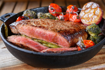 Beef steak medium rare with vegetables on a cast iron skillet. still life of food in low key. a dish of European cuisine. food in rustic style