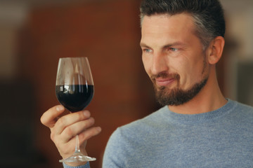 Handsome middle-aged man tasting red wine, close-up