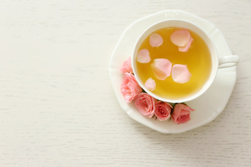 Cup of tea with roses on wooden background