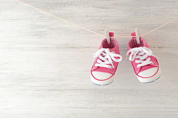 Baby sport shoes hanging on the clothesline on light wooden background