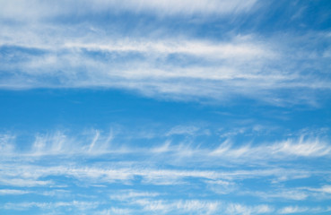 Striped white clouds and blue sky. Cloudscape over horizon.