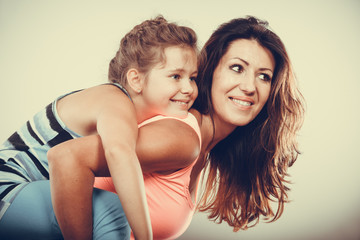 Mother parent giving kid piggyback ride.