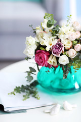 Beautiful bouquet of colourful roses in glass vase on white table