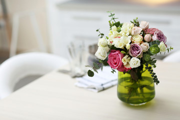 Beautiful bouquet of colourful roses in glass vase on the kitchen table
