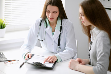 Doctor and  patient  sitting at the desk near the window in hospital