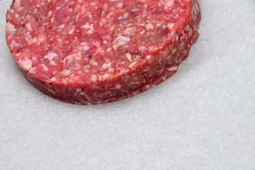 Raw meat burger, hamburger on white parchment
