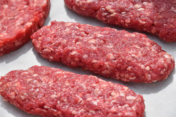 Raw red meat long kebabs, cutlets on parchment
