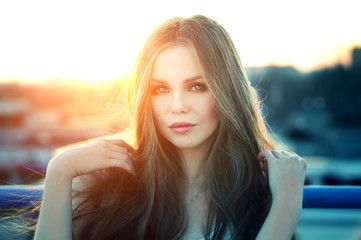 Outdoor portrait of young pretty sexy woman with magic eyes posing at roof at the end of bright sunset. Lovely soft back light.