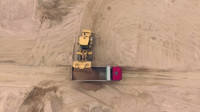 Aerial view of bulldozer pouring sand into truck