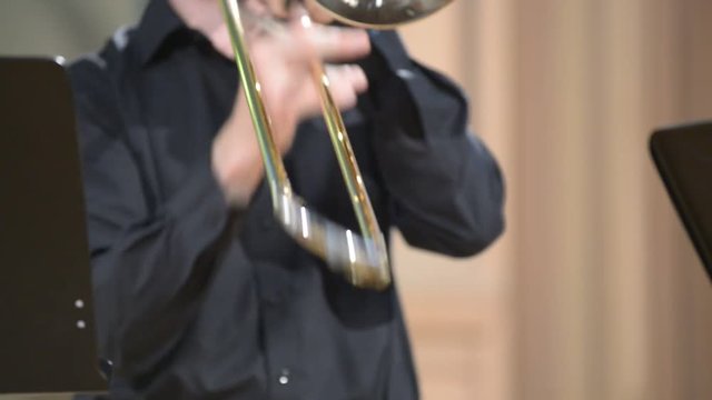 Trombonist playing the trombone, close-up, blurred defocused background