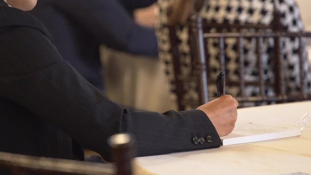 Man takes notes at a conference lecture