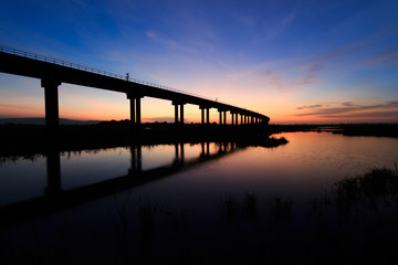 Fototapeta na wymiar train bridge over the dam at sunset in Thailand