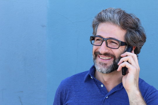 Casual man talking on mobile phone isolated on blue with copy space