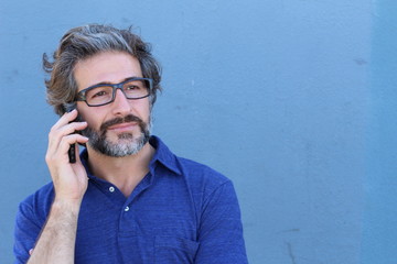 Smiling mature businessman talking on the cell phone with copy space