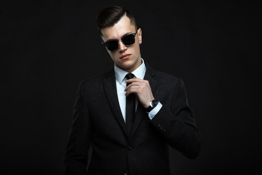 Stylish young man in suit and sunglasses. Business style. Fashionable image. Office worker. Sexy man standing and looking at the camera