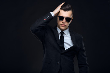 Stylish young man in suit and sunglasses. Business style. Fashionable image. Office worker. Sexy man standing and looking at the camera
