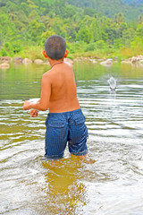 boy playing in the river throwing stones to the water