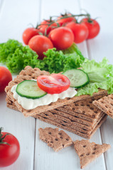 Close up of crispbreads with soft cheese and vegetables