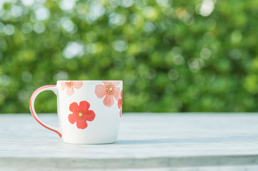 Closeup cute cup of coffee on blurred concrete desk and garden view in the morning textured background