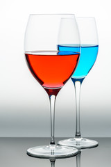 two glasses with blue colored water and wine