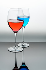 two glasses with blue colored water and red wine