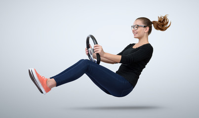 Young girl in glasses driver car with a wheel