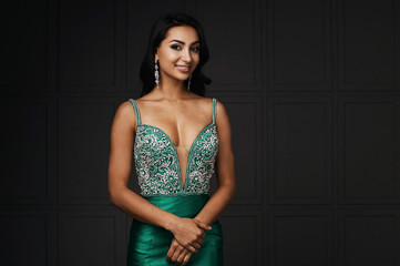 raven haired indian lady posing in studio against gray wall