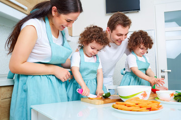 Daughters twins, dad and mom cook in the kitchen. A happy family