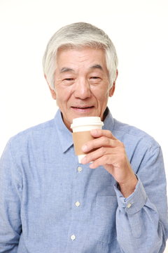 持ち帰りのコーヒーを飲む高齢者