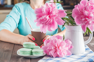 Macaroons cookies, espresso coffee cup and peony flower on woode