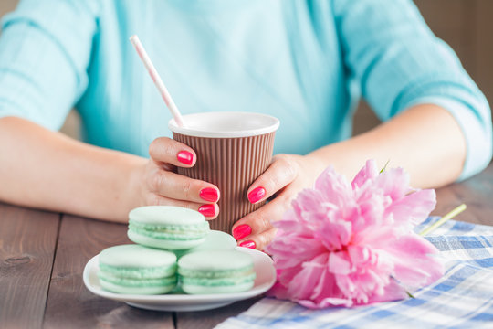 Paper cup of coffee and macaroons on table