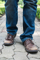 Man wearing jeans walking on the path to the park or garden