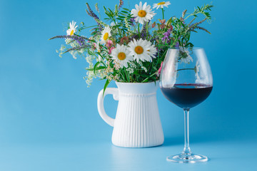 Glass of Red Wine with Wildflowers on blue background