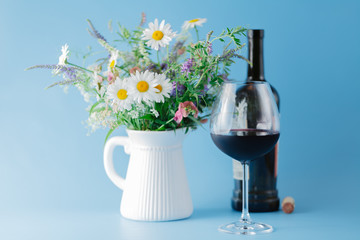Glass of Red Wine with Wildflowers on blue background