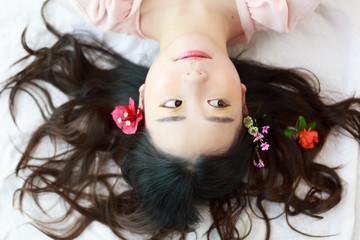 Naklejka premium A cute asian girl lying on the white cloth