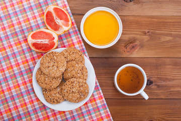 Cup of tea and citrus honey cookies on a wooden table.