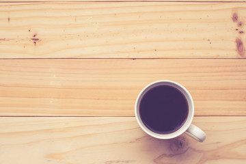 Coffee cup on the wooden table in Vintage tone